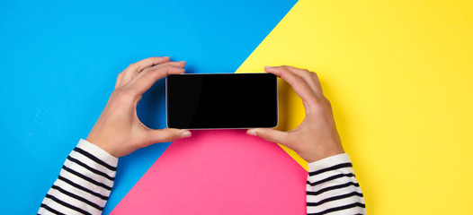 Wall Mural - Woman's hands with smartphone on colorful background.