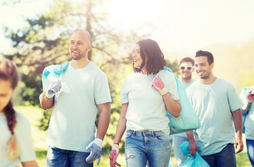 Sticker - volunteering, charity, cleaning, people and ecology concept - group of happy volunteers with garbage bags walking in park