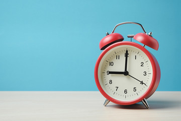 Red vintage alarm clocks on wooden table and light blue background wall