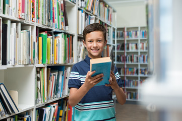 Wall Mural - Boy holding book in library at school