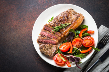 Grilled beef striploin steak with fresh salad top view.