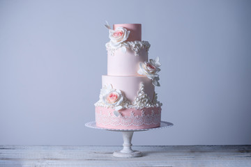 Beautiful elegant four tiered pink wedding cake decorated with roses flowers. Concept floral from sugar mastic