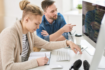 busy concentrated web designer making notes in diary while listening to mentors recommendations, the