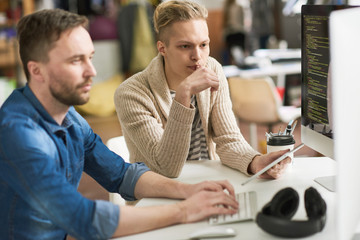Team of startup programmers working on code while brainstorming on web script for modern application in office