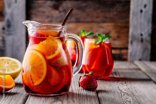 Fotografía Homemade red wine sangria with orange, apple, strawberry and ice in pitcher and