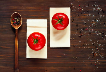 Wall Mural - wooden spoon with spices and red tomatoes lie on the plates of dough for lasagna on a dark background with spices, close-up, top view, concept of cooking italian pasta, copy space, minimalism