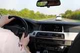 Fototapeta  - Kierowca kieruje nowoczesnym samochodem osobowym na autostradzie w słoneczny dzień.