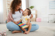 © Africa Studio - Cute baby and mother playing on floor at home