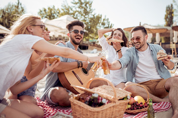 Canvas Print - Group of happy young people having a picnic on the beach