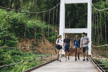 Group of friends walking on the bridge in a tropical countryside adventure and journey concept