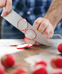 Canvas Print - Close up male hands chopped radish wooden table close up