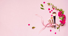 Various Brushes For Make-up And Pink Spring Flowers On A Pink Pastel Background Top View With Copy Space. Makeup Accessories Top Flat Lay