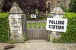 British election polling station sign hanging on post next to a gate and hedge in the UK