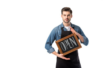 Wall Mural - portrait of young waiter in apron with open blackboard isolated on white