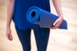 © StudioWout - Young woman holding yoga mat
