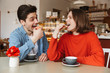 © Drobot Dean - Portrait of happy couple man and woman dating in cozy bakery, and eating macaroon biscuits