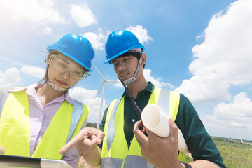 Wall Mural - Two male and female engineers are working at the wind turbine.