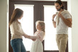 © fizkes - Caring mother helping little daughter dressing for walk with dad, family talking getting ready to go out standing in house hall, divorced young couple shared parenting and joint custody concept