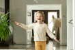 Cute funny boy running in hallway exploring big luxury house relocating with parents, excited child son jumping playing entering new modern home, happy kid enjoying moving day with family concept