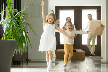 excited funny kids boy and girl running inside luxury big modern house on moving day, cute children 