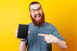 © Vulp - Amazed smiling bearded man wearing sunglasses and poiting at blank screen of tablet