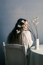Woman Sitting Near Table With Flowers