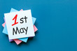 May 1st. Day 1 of may month, calendar on pile of notes at blue background with copy space for template or mockup. Spring time, International Labour day
