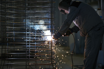 Welder man welds at the factory. Industrial Worker welder welding steel structure for concrete pipe. Industry manufacturing concept