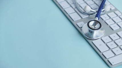 A medical stethoscope near a laptop on a wooden table, on white