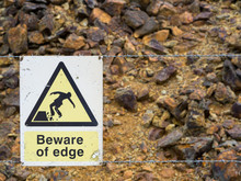 Warning Sign At The Edge Of Unstable Cliff