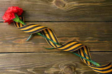 Red flower and St. George ribbon shaped as a nine symbol of world war II on wooden background.