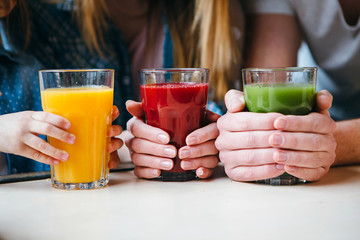 Family holding a glass of juice in hands.