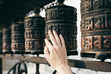 Buddhist Prayer Drums With Close-up Mantras.The Female Hand Touches The Buddhist Prayer Drum, Nepal.The Interaction Of Human Energy And The Buddhist Prayer Drum.the Girl Turns The Prayer Drum.