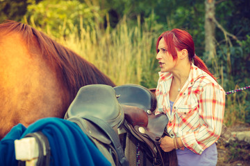 Poster - Cowgirl getting horse ready for ride on countryside