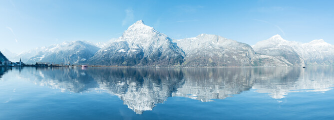 Wide mountain panorama of the Alps in the snow. Grandiose panorama of the snow-capped mountains. Reflections in the water of a mountain lake. Alps in Switzerland. Canton Uri.