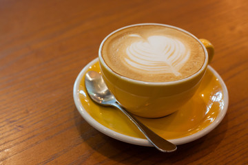 Wall Mural - Cappuccino in a cup on a wooden table in a coffee shop