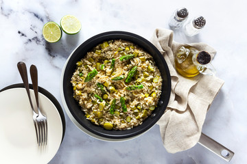 Wall Mural - risotto with asparagus in a frying pan on a white marble table. shot from above. vegan and vegetarian healthy Italian cuisine.