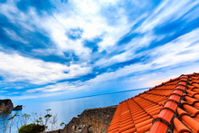 Wide Angle View From The Roof Of Red Tiles To Landscape. Dramatic Sky With Storm Clouds Over Sea. Bird's Eye View. Photo With A Tilted Horizon.