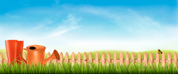Poster - Rubber boots with watering can in a green grass on garden background. Vector