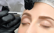 Microblading. Cosmetologist Making Permanent Makeup. Attractive Woman Getting Facial Care And Tattoo Eyebrows
