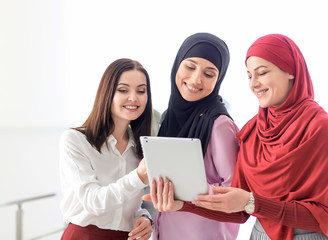 Wall Mural - Muslim businesswoman with coworkers on light background