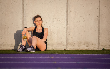 Canvas Print - Fitness woman resting after training on stadium running track