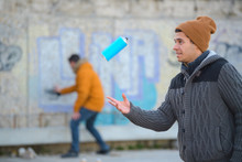 Men Writing Graffiti And Playing With Spray Can