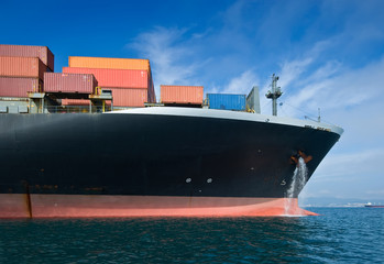 The bow of a huge container ship at anchored in the roads.