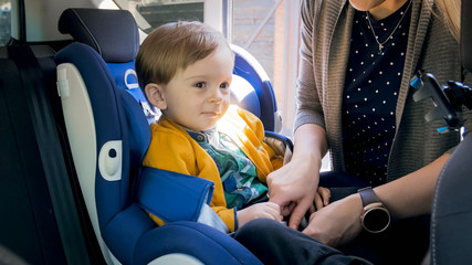 Adorable smiling toddler boy sitting in car safety seat