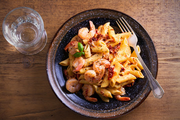 Wall Mural - Shrimp penne with sun dried tomatoes and basil in creamy mozzarella sauce. Pasta with shrimps in bowl on wooden table. overhead, horizontal