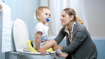 Wall Mural - Young caring mother teaching her boy using toilet