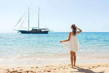 Happy woman in summer white dress on beach. girl relaxing and enjoying peace on vacation