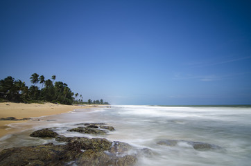 Wall Mural - wild tropical island and rocky sea shore under bright sunny day and blue sky background.