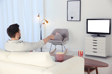 Canvas Print - Young man watching TV on sofa at home